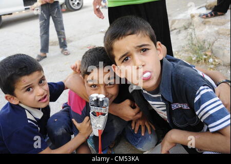 Azaz, Siria. Il 5 ottobre 2012. La vita dei bambini che sono in qualche modo cercando disperatamente di rimanere vivo e crescere in mezzo alla carneficina e caos attorno a loro é pur conservando la loro ebullience ad essere bambini ! AZAZÑIn Siria settentrionale, il 15 agosto almeno 80 persone sono state uccise in un'zaz come risultato del bombardamento aereo dai siriani Air Force Base di attivisti dell'opposizione e medici locali. Foto Stock