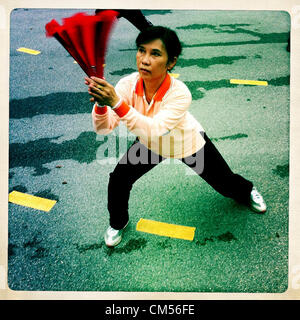 Il 7 ottobre 2012 - Bangkok, Thailandia - Le donne fanno Tai Chi esercita con ventole colorate nel Parco Lumphinee in Bangkok. Parco Lumphinee è 142 acri (57,6-ettaro) park a Bangkok, in Thailandia. Questo parco offre rari aprire uno spazio pubblico, alberi e campi da gioco in congestionata capitale tailandese. Esso contiene un lago artificiale dove i visitatori possono noleggiare barche. Corsi di ginnastica e di esercitare i club a raggiungere nel parco per la mattina presto gli allenamenti e i sentieri intorno al parco per un totale di circa 1,55 miglia (2.5ÃŠkm) di lunghezza sono una zona popolare per gli amanti del jogging. La bicicletta è consentito solo durante il giorno tra i tempi di 5am alle 3pm. Foto Stock