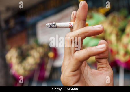 Ottobre 14, 2012 - Bangkok, Tailandia - un uomo detiene una sigaretta mentre si fuma in una strada a Bangkok, Thailandia. La Tailandia e le filippine sono coinvolti in una disputa sulle tasse di sigaretta. Philippine scambi funzionari affermano che la Thailandia tariffe sleali una tassa di importazione sui Filippini di sigarette. Funzionari tailandesi hanno risposto che essi hanno preso la materia oggetto della consulenza. Philippine hanno detto i funzionari possono portare la questione all'Organizzazione mondiale del commercio se la Tailandia non risponde da ott. 15. (Credito Immagine: © Jack Kurtz/ZUMAPRESS.com) Foto Stock