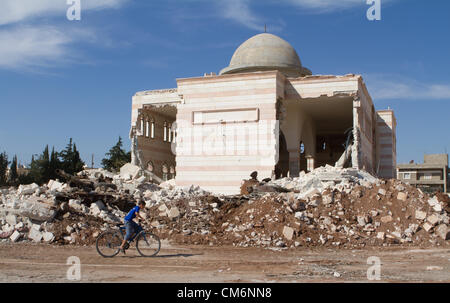 Azaz, Siria. Il 17 ottobre 2012. Un ragazzo corse una bicicletta passato un serbatoio distrutto nei pressi di una moschea danneggiato in un'zaz, Siria il 17 ottobre 2012. Credito: PixelPro / Alamy Live News Foto Stock