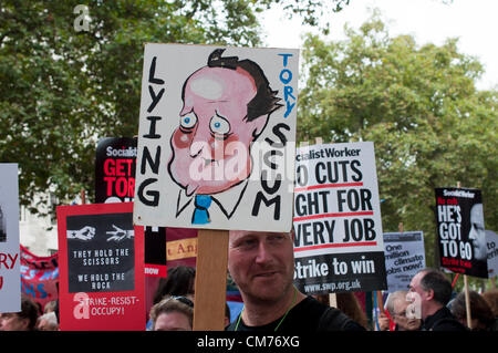 20/10/2012, Londra UK. Un uomo brandisce una targhetta con un poco lusinghiero dipinta a mano ritratto di David Cameron come sindacati stadio a proteste di massa contro il governo del Regno Unito di tagli di austerità. Un marzo attraverso il centro di Londra è culminato in un rally in Hyde Park Foto Stock