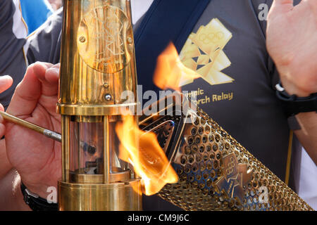 Derbyshire, Regno Unito. Venerdì 29 Giugno 2012. La fiamma olimpica passando dalla torcia a lanterna custodito da Met. Torcia di polizia security team Chatsworth House. Foto Stock