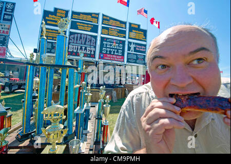 Toronto, Canada. Il 30 giugno 2012, un visitatore gode di costolette di maiale a Toronto ribfest. Il festival ha attirato i punteggi di Torontonians al Centennial Park motivi durante il lungo weekend che ha segnato il Canada Day celebrato il 1 di luglio. Foto Stock