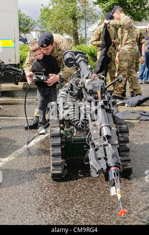Carrickfergus, 30/06/2012 - Forze Armate giorno. Soldato da 321 EOD Squadron, mostra un ragazzo giovane come operare un Northrop Grumman carriola comandato a distanza bomb disposal robot Foto Stock