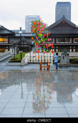 Luglio 7th, 2012 : Tokyo, Giappone - come una consuetudine di Tanabata Festival, una tradizionale festa il 7 luglio di ogni anno, un uomo tese un desiderio su un bambù a Zojoji, o Tempio Zojo Tempio, a Shibakouen, Minato a Tokyo, in Giappone il 7 luglio 2012. Anche se il festival è stato supposto per celebrare le stelle, pioveva e nuvoloso di quest'anno. (Foto da Koichiro Suzuki/AFLO) Foto Stock