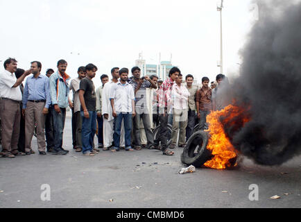 Manifestanti arrabbiati bruciare pneumatici stradali di blocco durante una dimostrazione dopo l uccisione di attivisti di un partito politico a Nazimabad area in Karachi giovedì, 12 luglio, 2012. Foto Stock