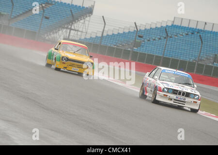 Xx Luglio 2012, Silverstone, Regno Unito David bracciale e Mark Smith della BMW E30 M3, e Michael Bell's Ford Escort sotto la pioggia durante le qualifiche per la Fujifilm Touring Car Trophy 1970-2000 gara a Silverstone Classic 2012 Foto Stock