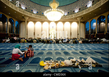 London, Regno Unito - 21 Luglio 2012: due bambini di sedersi vicino a un banchetto mentre i fedeli musulmani pregano dopo la rottura del digiuno del Ramadan al London Central moschea di Regent's Park Foto Stock