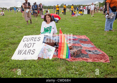 Una donna si appoggia durante la visualizzazione di un segno e una bandiera arcobaleno, come ella attende l'AIDS marzo a Washington DC a start - Luglio 22, 2012, Washington DC, Stati Uniti d'America Foto Stock