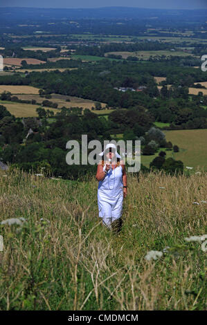 Sussex, Regno Unito. Il 25 luglio 2012. Una donna cammina di mangiare un gelato sul South Downs vicino Ditchling Beacon Foto Stock