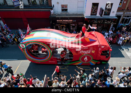 La Torcia olimpica arriva giù Coldharbor Lane in Brixton, Londra, Regno Unito. I torchbearer è protetto dalla polizia in grigio sportswear e il relè è preceduta da sponsor per i veicoli che sono fischiato dalla folla. 26 Luglio 2012 Foto Stock