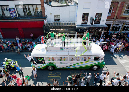 La Torcia olimpica arriva giù Coldharbor Lane in Brixton, Londra, Regno Unito. I torchbearer è protetto dalla polizia in grigio sportswear e il relè è preceduta da sponsor per i veicoli che sono fischiato dalla folla. 26 Luglio 2012 Foto Stock