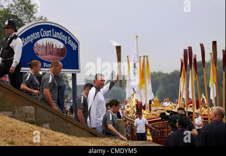 Venerdì 27 Luglio, 2012. Sir Matthew Pinsent portando la torcia olimpica per la chiatta sul Fiume Tamigi a Hampton Court il quale sarà portato a Londra. I vogatori stanno tenendo i loro remi aloft. In Inghilterra. Credito: Cefa Picture Library / Alamy Live News. Foto Stock