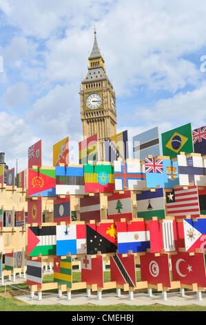 La piazza del Parlamento, Londra, Regno Unito. Il 30 luglio 2012. Big Ben visto sopra la torre delle bandiere, le pareti delle bandiere di legno che includono tutte le nazioni che partecipano alle Olimpiadi di Londra 2012. L'installazione è stata progettata dagli architetti AY. Foto Stock