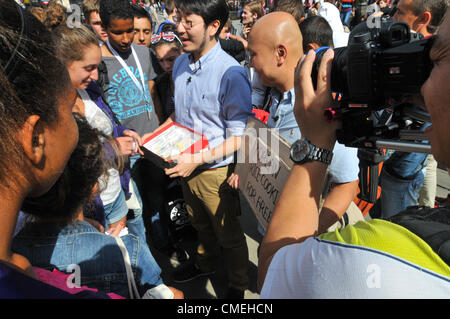 Piccadilly Circus, Londra, Regno Unito. Il 30 luglio 2012. Un TV coreana equipaggio dare via libera i cookie coreana. Le Olimpiadi di Londra 2012 sta attirando troupes televisive provenienti da tutto il mondo a coprire i giochi e cattura lo spirito e l'atmosfera della città che ospita i giochi. Foto Stock