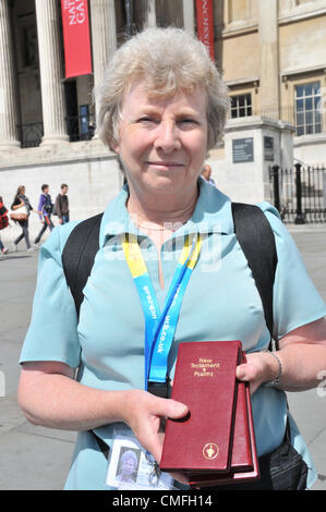 Il 3° agosto 2012. Trafalgar Square, Londra, Regno Unito. Il 3 agosto 2012. Una donna che indossa un "Olympic' distintivo di stile mani Gideons Nuovo Testamento in Trafalgar Square. I gruppi religiosi sono nel centro di Londra, molti utilizzando le Olimpiadi di temi in alcune delle loro attività per attrarre nuovi credenti. Foto Stock