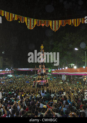 Festival di Dahi Handi celebra il dio indù Krishna il compleanno. Come parte della celebrazione e del folklore, i team di giovani uomini e ragazzi di competere per costruire una piramide umana al fine di distruggere una pentola di cagliata sospesa 30piedi in aria. Foto Stock