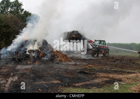 11 ago 2012. Cappella Brampton. Northamptonshire U.K. 11 agosto 2012. 600 balle di erba elefante, distrutto da un incendio a fianco di Merry Tom Lane, 200 metri dal modo Midshires. Fire equipaggi erano in operatori la maggior parte della notte, un equipaggio di rilievo ha assunto a 0930 questa mattina. Il miscanto (comunemente noto come erba elefante) è una ad alta resa del raccolto di energia che cresce di oltre 3 metri di altezza produce un raccolto ogni anno senza la necessità di reimpianto. utilizzati prevalentemente per la produzione di materie prime ma anche come biocarburante. Credito: Keith J Smith. / Alamy Live News Foto Stock