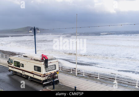 Aberystwyth Wales UK, sabato 2 novembre 2013 un proprietario caravan protegge il suo veicolo come avvisi vengono rilasciati per gale force venti in Aberystwyth Wales UK. Le risorse naturali del Galles (NRW) detto dieci avvertenze alluvione sono attualmente in vigore nelle zone costiere del Galles, con le preoccupazioni su alta marea. Raffiche di colpire 70 nodi (80mph) sono state riportate sulle coste esposte. Photo credit: keith morris/Alamy Live News/Alamy Live News Foto Stock