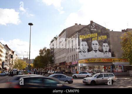 Berlin-Wedding, Germania. 30 ott 2013. Un sporting buon costruttore pubblicizza con le facce dei fratelli Girolamo (L-R), George e Kevin-Prince Boateng su una parete di un edificio in Berlin-Wedding, Germania, 30 ottobre 2013. Schalke's pro soccer player Kevin-Prince Boateng avrebbe imparato a giocare a calcio in questa gabbia. Foto: Joerg Carstensen/dpa/Alamy Live News Foto Stock