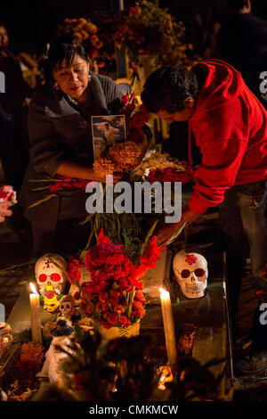 I membri della famiglia accendono le candele in onore del morto a San Felipe de Aqua cimitero durante il Giorno dei Morti Festival noto in spagnolo come d'un de Muertos il 2 novembre 2013 a Oaxaca, Messico. Foto Stock