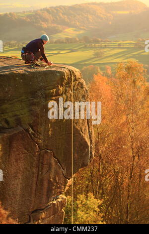 Un scalatore di pietra lo affronta Froggatt sopra il bordo della Valle del Derwent su un bel giorno di autunno nel Peak District, Derbyshire, in Inghilterra, Regno Unito Foto Stock