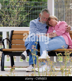 Bianco senior caucasico giovane uomo e donna che dorme su una panchina nel parco. Foto Stock