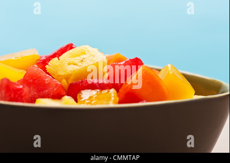 Una scodella di miste di una insalata di frutta tropicale di fronte a sfondo blu Foto Stock