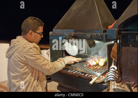 Chef di cottura degli alimenti su Benalmadena fronte mare all'aperto su un barbecue su carbone caldo Foto Stock