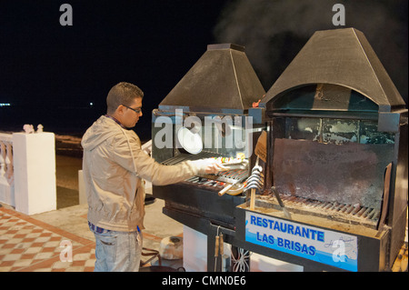 Chef di cottura degli alimenti su Benalmadena fronte mare all'aperto su un barbecue su carbone caldo Foto Stock