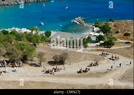 Rodi. La Grecia. Vista dei turisti su asini di salire lungo la pendenza dell'acropoli di Lindos e castello dei cavalieri. Molto di Lindos Foto Stock