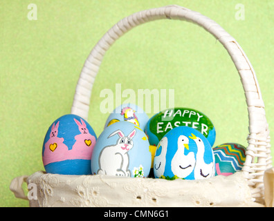 Dipinto a mano le uova di Pasqua in cesto contro sfondo verde chiaro Foto Stock