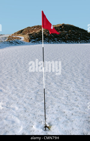 Bandiera su una coperta di neve del campo da golf links in Irlanda in inverno Foto Stock