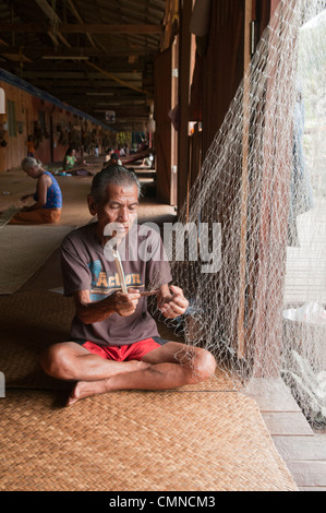 Iban longhouse chief mende sue reti da pesca al Nanga Sumpa longhouse nel Sarawak, Borneo Malaysia Foto Stock