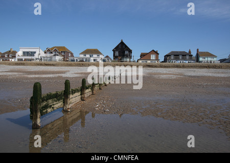 Camber Sands lungomare case da spiaggia con groyne in primo piano. Foto Stock