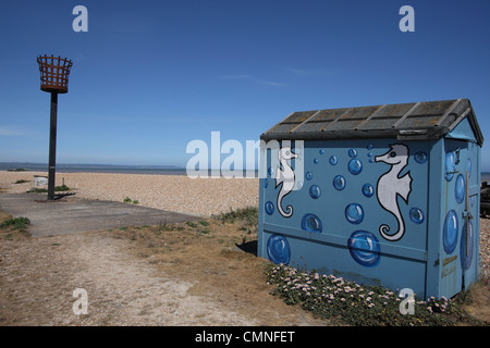 Romney Marsh Littlestone Beach Hut dipinta con i cavallucci marini design e la torcia sul lungomare il faro a luce rotante. Foto Stock