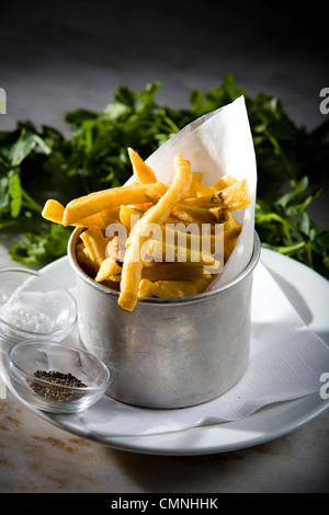 Patate fritte servite in pentola in alluminio con insalata sul lato. Foto Stock