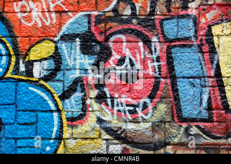 Parete con strati sovrapposti di disordine graffiti e tag. Urban street art background. Foto Stock