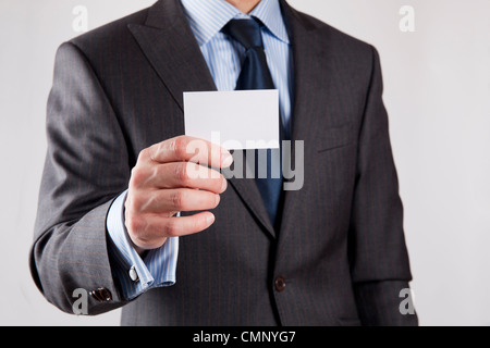 Imprenditore in abito grigio e una maglietta blu con una cravatta blu, mostra business card con copia spazio poco profondo, dept di campo, isolato Foto Stock