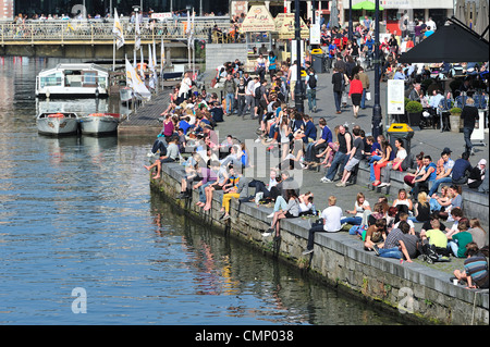 Turisti e studenti godendo il primo sole di primavera da the Waterside lungo il Graslei a Gand, Belgio Foto Stock