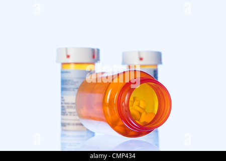 Arancione tre flaconi portapillole in polvere la luce blu sulla superficie trasparente. Grande Vaso in primo piano con le pillole, scoperchiate, marcato. Foto Stock