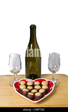 Una bottiglia di vino con gli occhiali e una piastra di burro di arachidi e biscotti al cioccolato su un tavolo Foto Stock