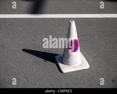 Un traffico di bianco a forma di cono con il rosso e il blu 'no parcheggio / nessun arresto' segno stampato su di esso. Foto Stock