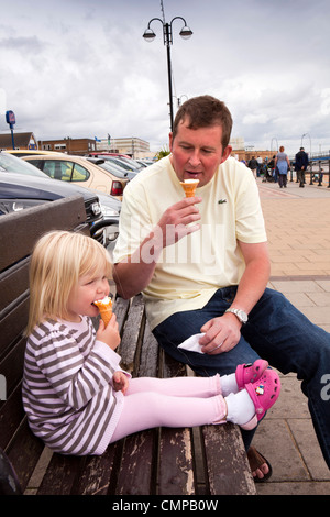 Regno Unito, Inghilterra, Lincolnshire, Cleethorpes, padre e figlia mangiare gelati sul lungomare Foto Stock