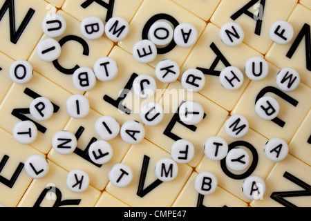 Perle bianche con lettere in nero rovesciato in maniera casuale su un mosaico di avorio con lettere più grandi Foto Stock