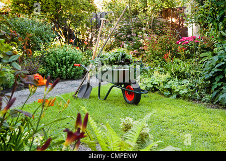 Sera dopo il lavoro nel giardino estivo con carriola, pala e rastrello - orizzontale Foto Stock