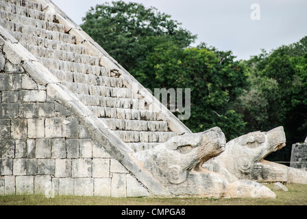 Tempio di Kukulkan delle teste di serpente di Chichen Itza Messico | CHICHEN ITZA, Yucatan, Messico — Teste di serpente in pietra scolpita affiancano la base della scala nord di El Castillo, le loro fauci aperte formano la testa del serpente piumato che sembra scendere dalla piramide durante la rappresentazione delle ombre all'equinozio. Il Tempio di Kukulcán, dedicato alla divinità del serpente piumato, fu eretto nel X secolo sulla cima di una piramide annidata precedente scoperta durante gli scavi degli anni '30. Foto Stock