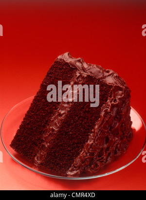 Anni sessanta fetta di due strati di torta al cioccolato sul piatto di vetro sfondo rosso Foto Stock