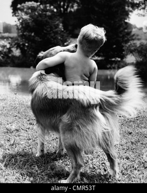 Negli anni quaranta anni cinquanta anni sessanta vista posteriore del ragazzo e abbracciando il cane Foto Stock