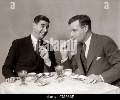 Negli anni Trenta due uomini illuminazione dopo cena sigarette sorridente Foto Stock